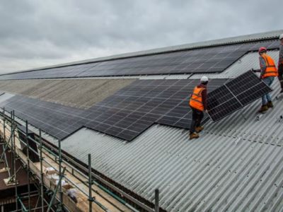 Staff standing on a depot roof installing solar panels