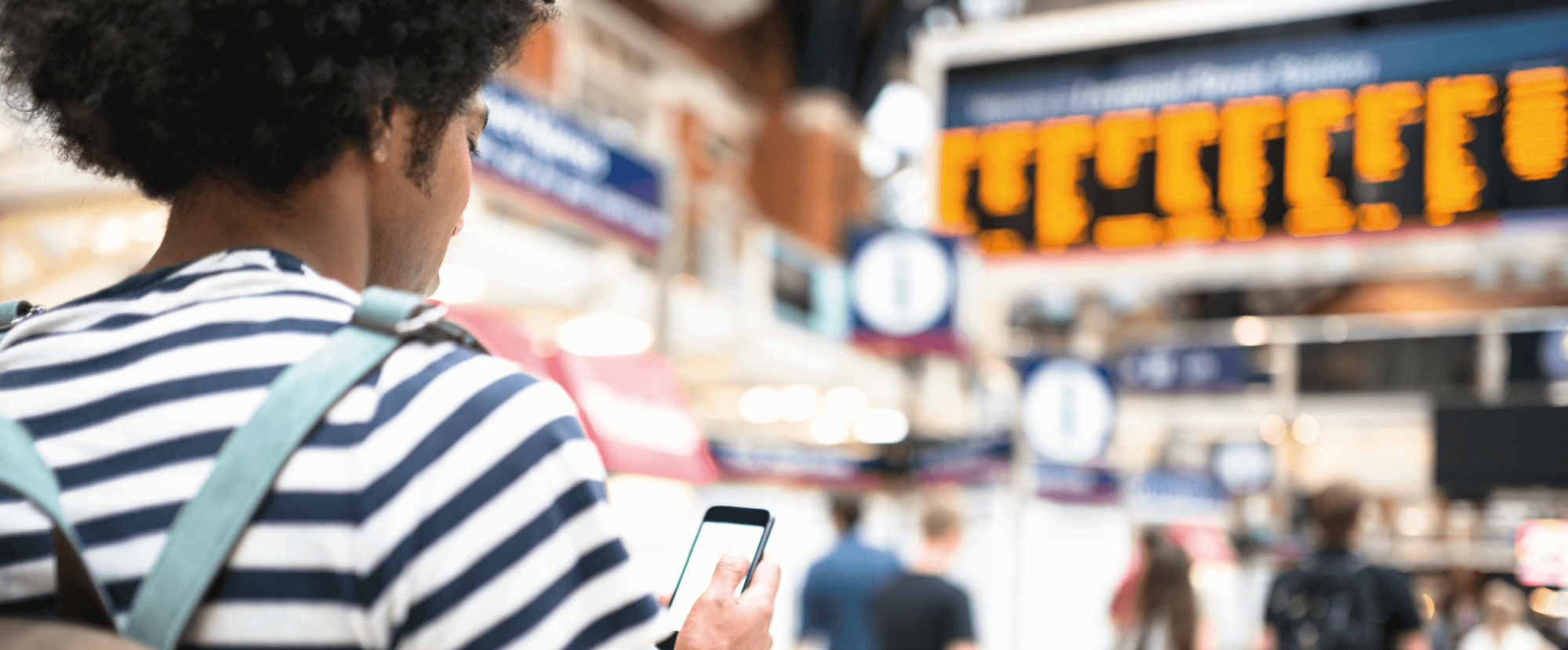 Male passenger in a station looking at his phone